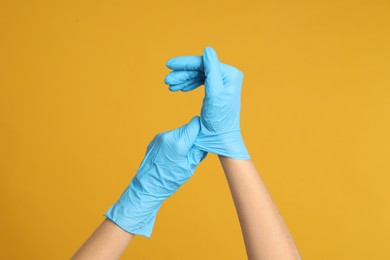 Photo of Doctor wearing medical gloves on yellow background, closeup