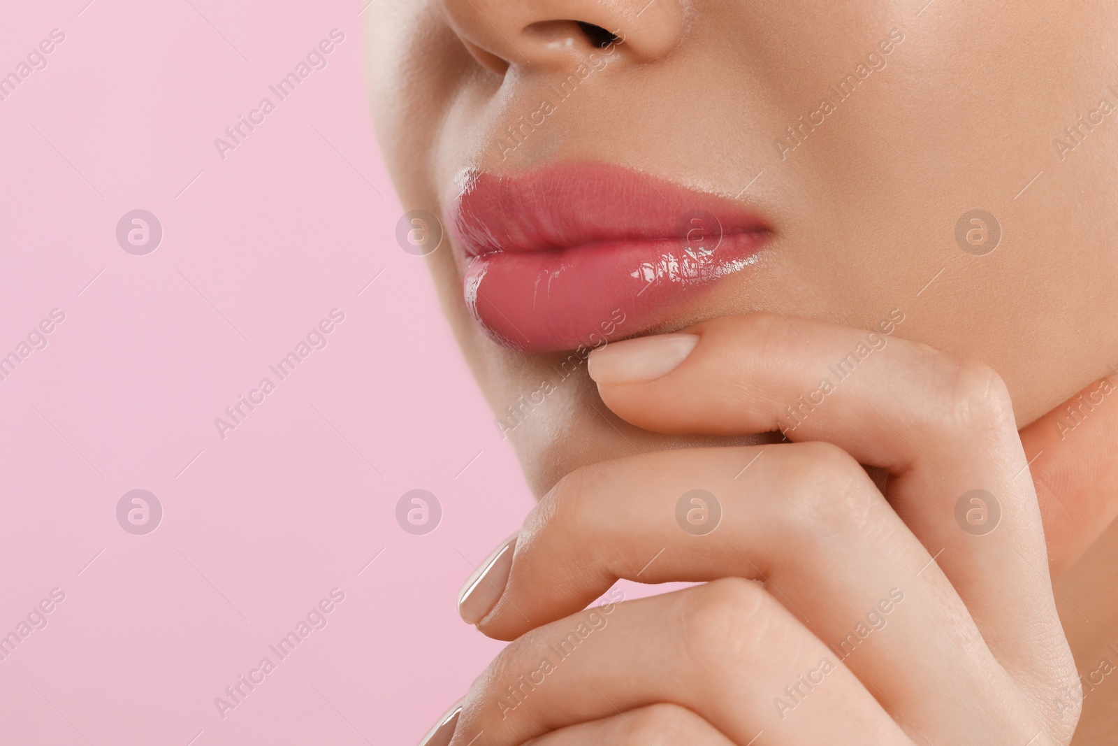 Photo of Young woman with beautiful full lips on pink background, closeup