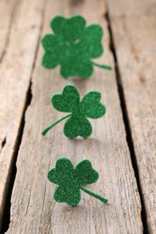 St. Patrick's day. Shiny decorative clover leaves on wooden table, selective focus