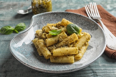 Photo of Plate with delicious basil pesto pasta on wooden table