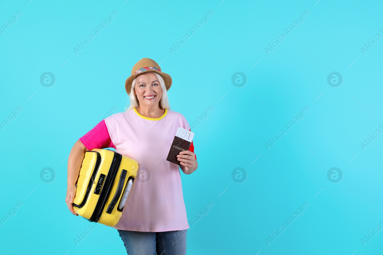 Photo of Senior woman with suitcase and passport on color background. Space for text