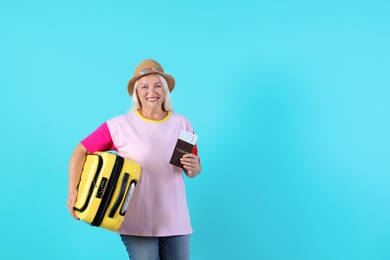 Photo of Senior woman with suitcase and passport on color background. Space for text