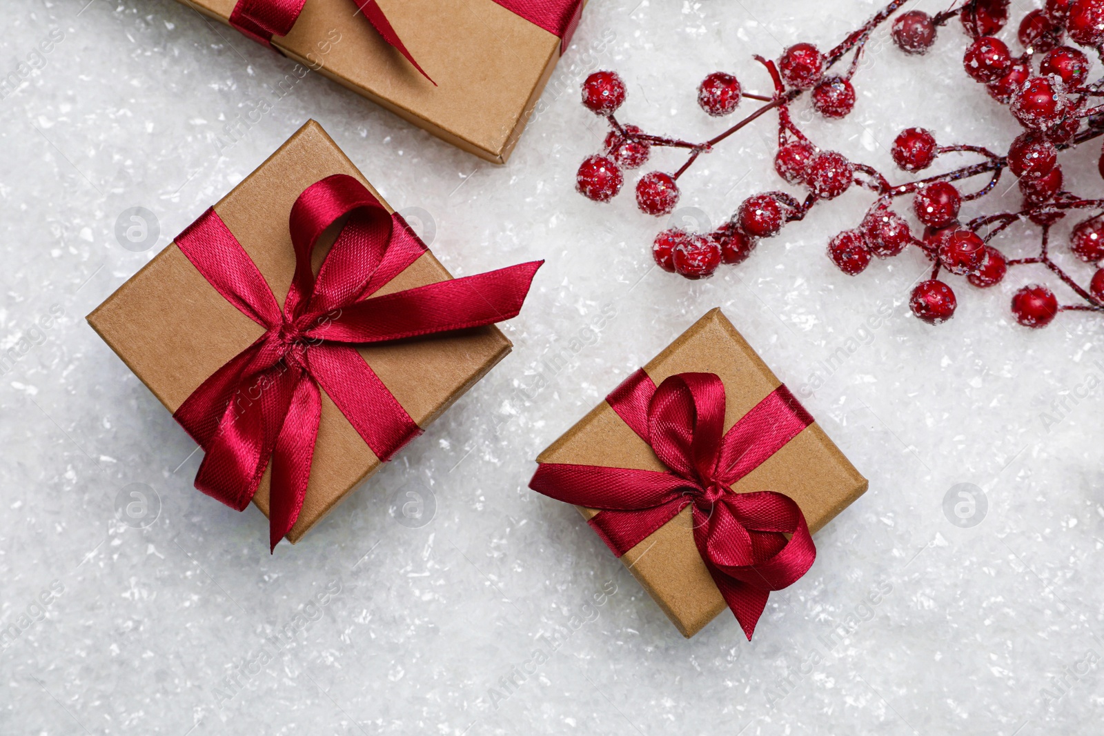 Photo of Gift boxes and decorative branches on artificial snow, flat lay. Christmas celebration