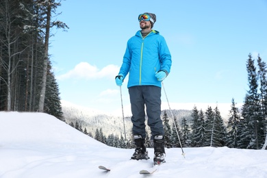 Man with ski equipment spending winter vacation in mountains