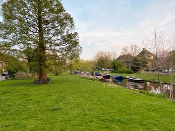 Photo of Beautiful view of canal with different boats near green lawn