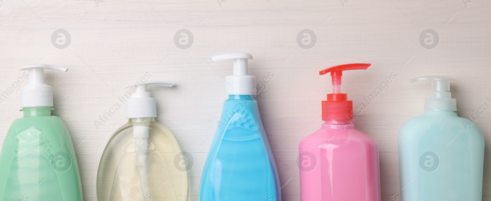 Image of Many different dispensers of liquid soap on white wooden table, flat lay with space for text. Banner design