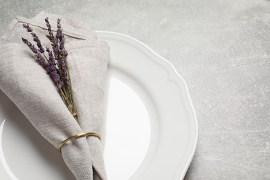 Photo of Plate with fabric napkin, decorative ring and lavender on gray background, space for text