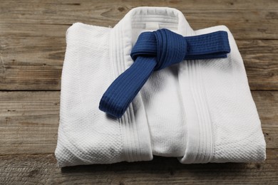 Photo of Blue karate belt and white kimono on wooden background