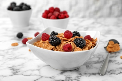 Photo of Bowl with cornflakes and berries on marble table. Whole grain cereal for breakfast