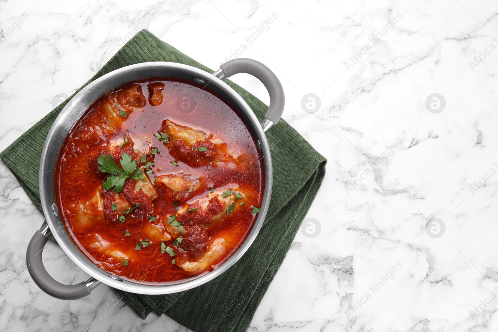 Photo of Delicious stuffed cabbage rolls cooked with homemade tomato sauce in pot on white marble table, top view. Space for text