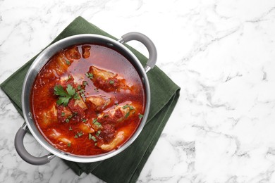 Photo of Delicious stuffed cabbage rolls cooked with homemade tomato sauce in pot on white marble table, top view. Space for text