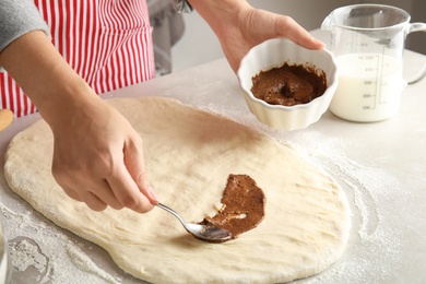 Woman making cinnamon rolls at table, closeup