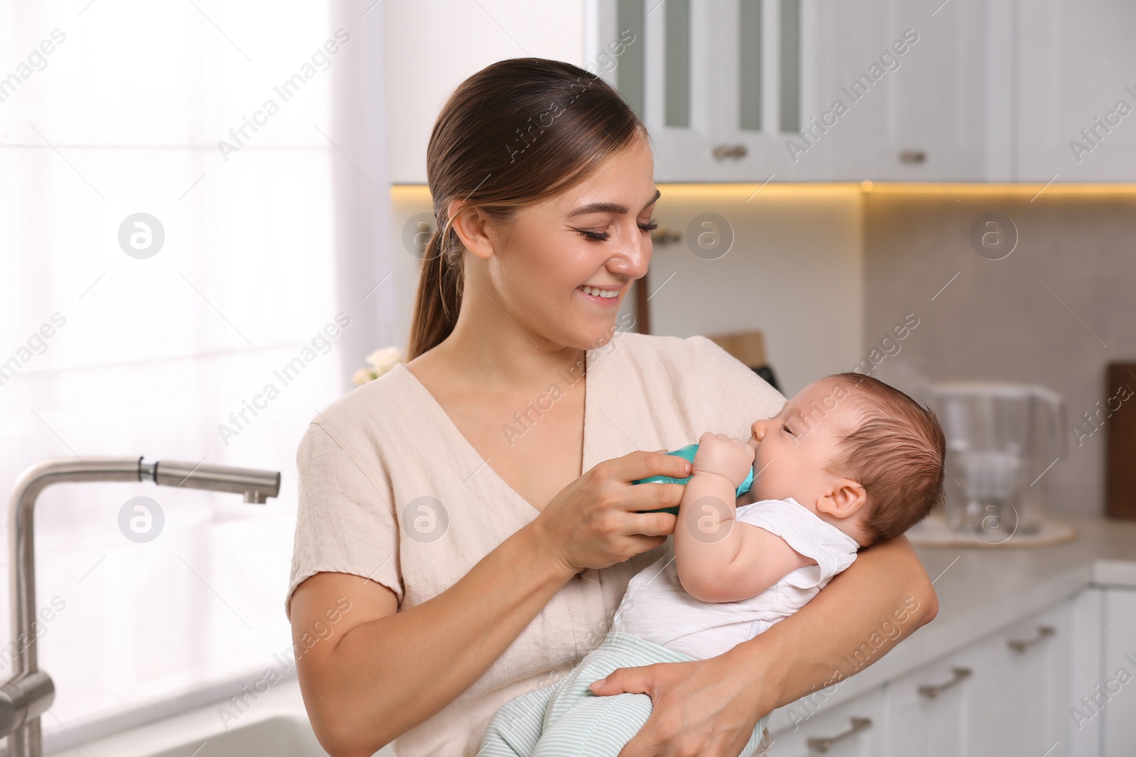 Photo of Mother feeding her cute child with infant formula indoors