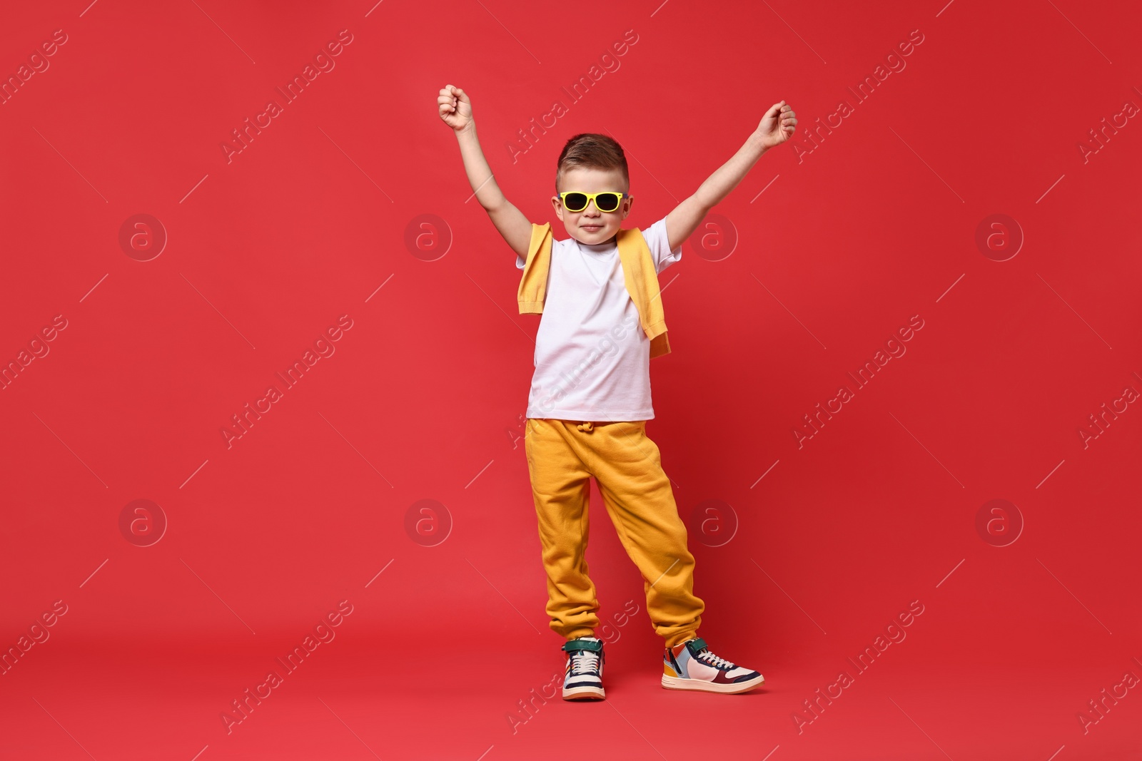 Photo of Happy little boy dancing on red background