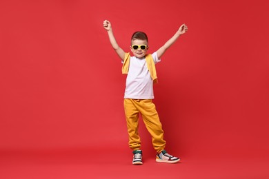 Happy little boy dancing on red background