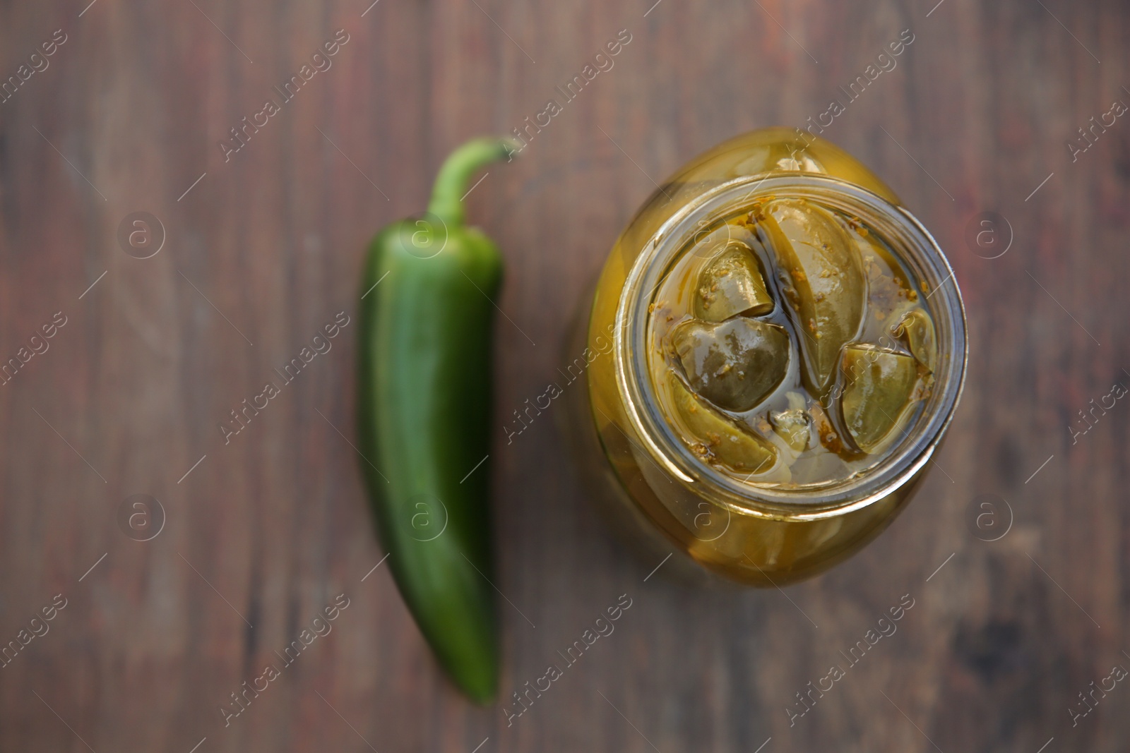 Photo of Fresh and pickled green jalapeno peppers on wooden table, flat lay. Space for text