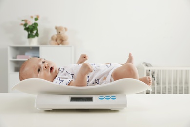 Cute little baby lying on scales in light room