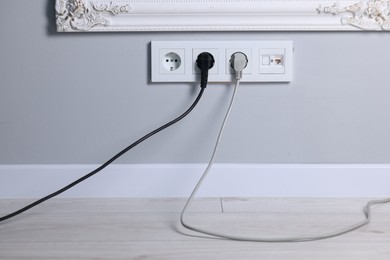 Power sockets and electric plugs on grey wall