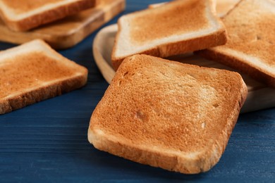 Photo of Slices of delicious toasted bread on blue wooden table, closeup