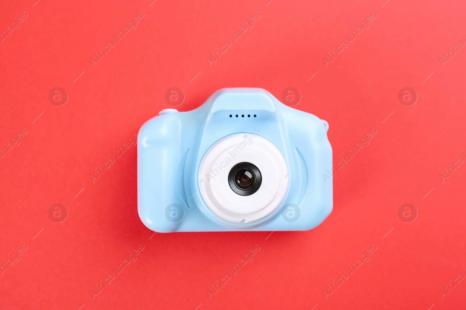 Photo of Light blue toy camera on red background, top view