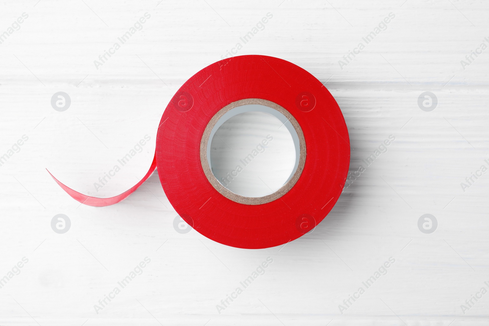 Photo of Red insulating tape on white wooden table, top view