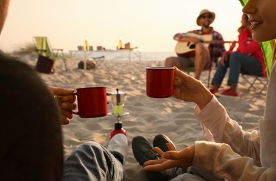 Friends resting on sandy beach, closeup. View from camping tent