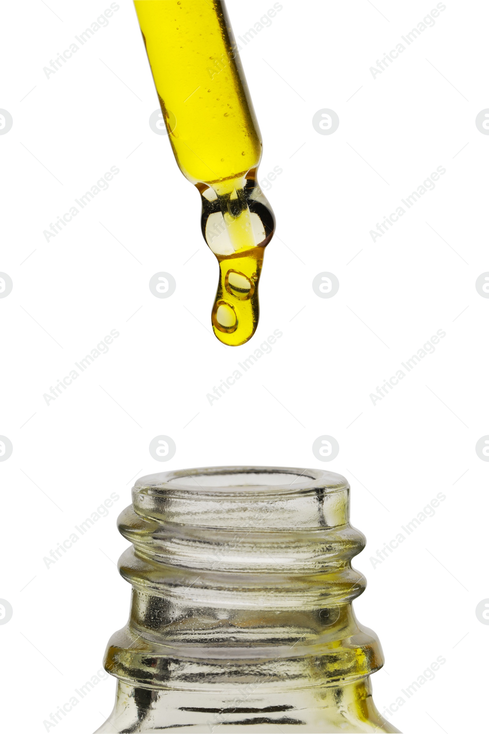 Photo of Dripping yellow facial serum from pipette into glass bottle on white background, closeup