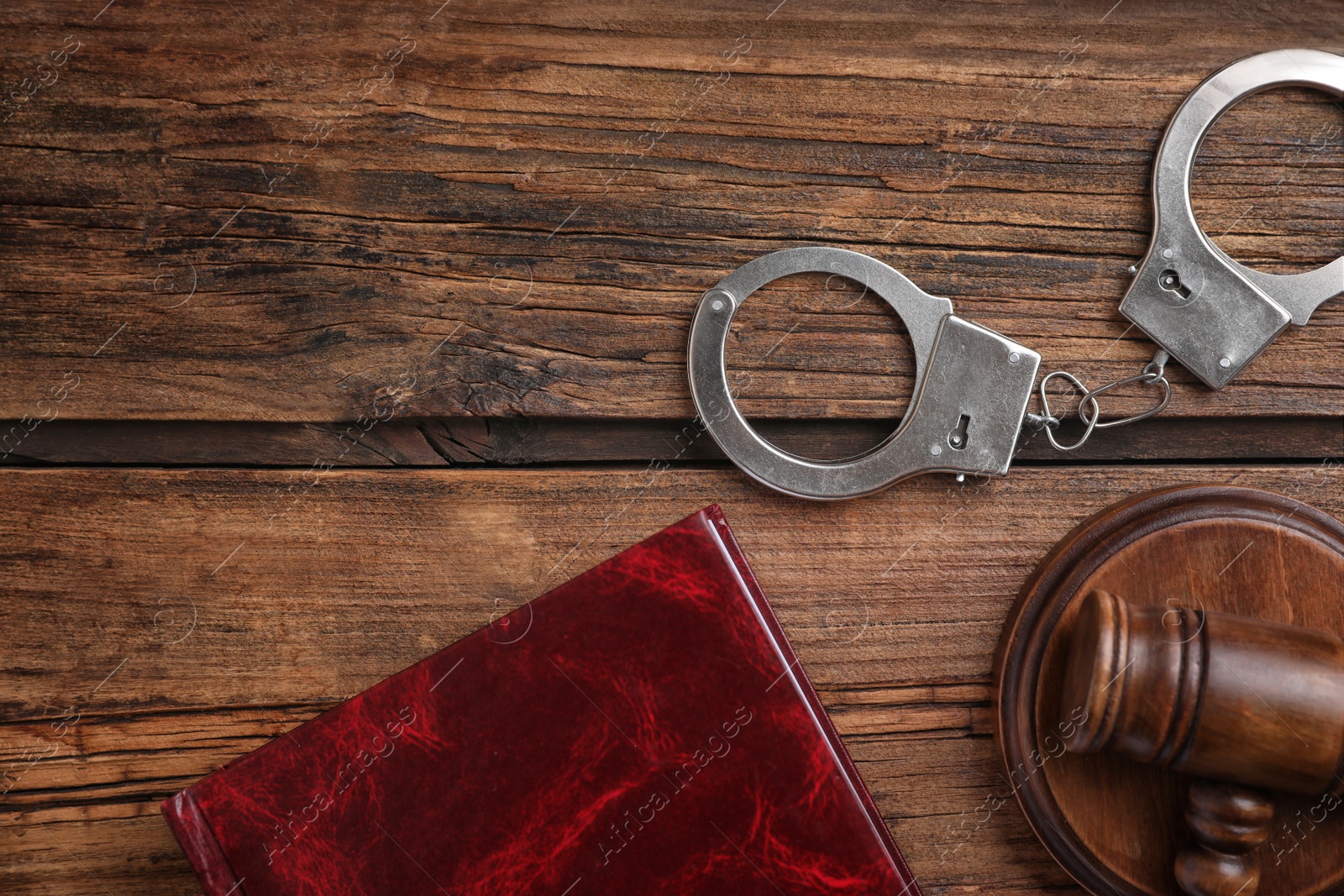 Photo of Book, handcuffs and gavel on wooden table, flat lay. Criminal law