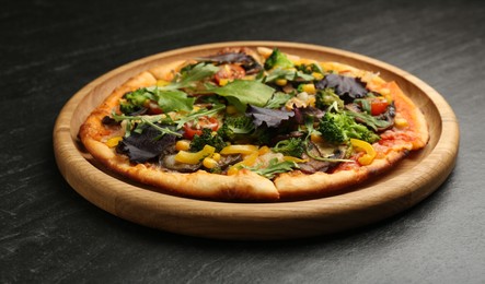 Photo of Delicious vegetarian pizza with mushrooms, vegetables and greens on black table, banner design