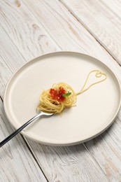 Photo of Heart made with spaghetti and fork on white wooden table