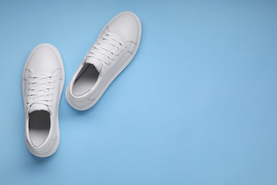 Photo of Pair of stylish white sneakers on light blue background, top view. Space for text