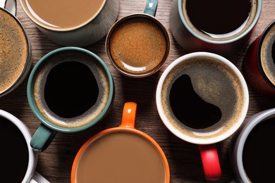 Photo of Cups of hot coffee on wooden table, flat lay