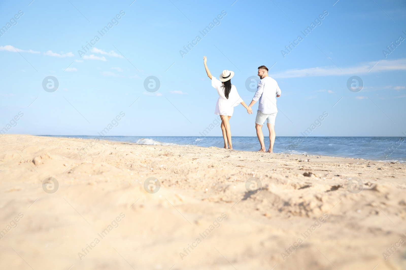 Photo of Happy young couple walking at beach on sunny day