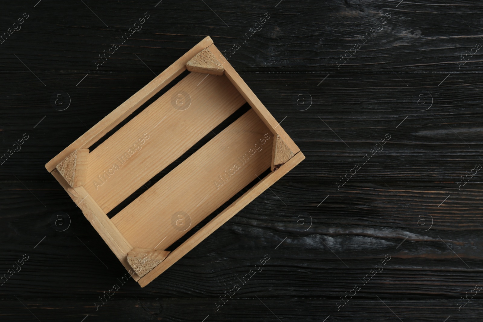 Photo of Empty wooden crate on dark background, top view with space for text