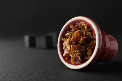 Photo of Red clay bowl of hookah with aromatic tobacco on black background, closeup. Space for text