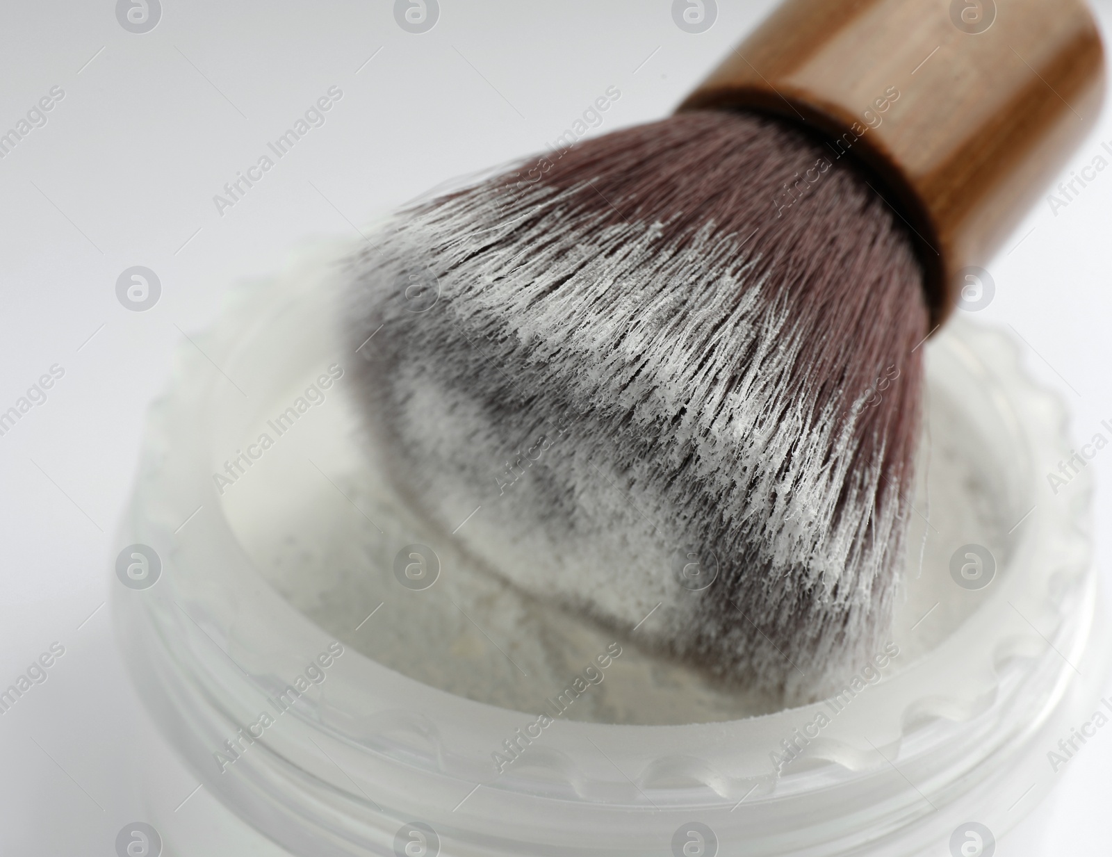 Photo of Brush with rice face powder on white background, closeup. Natural cosmetic