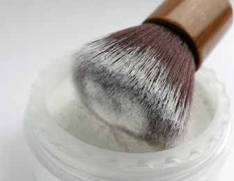 Brush with rice face powder on white background, closeup. Natural cosmetic