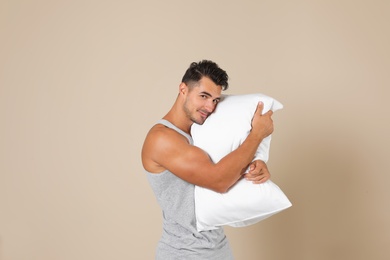 Photo of Young man with soft pillow on color background