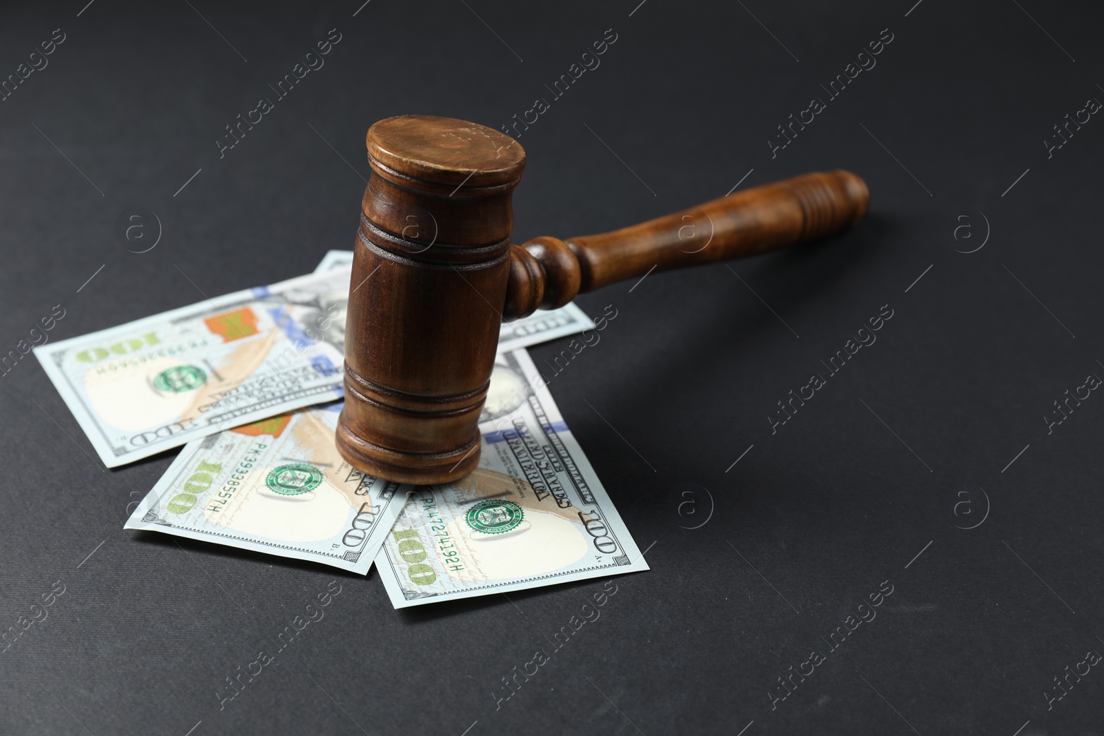 Photo of Law gavel with dollars on grey table