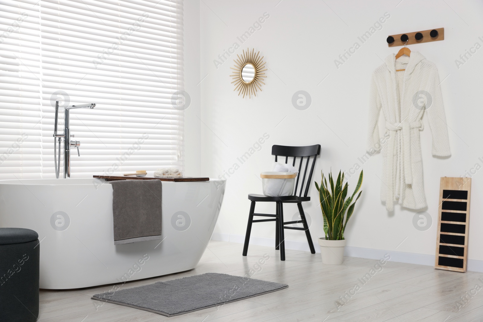 Photo of Stylish bathroom interior with ceramic tub, terry towels and houseplant