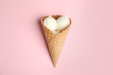 Photo of Delicious vanilla ice cream in wafer cone on pink background, top view
