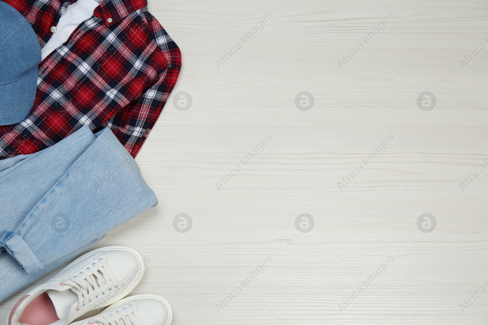 Photo of Set of stylish clothes and sneakers on white wooden table, flat lay. Space for text