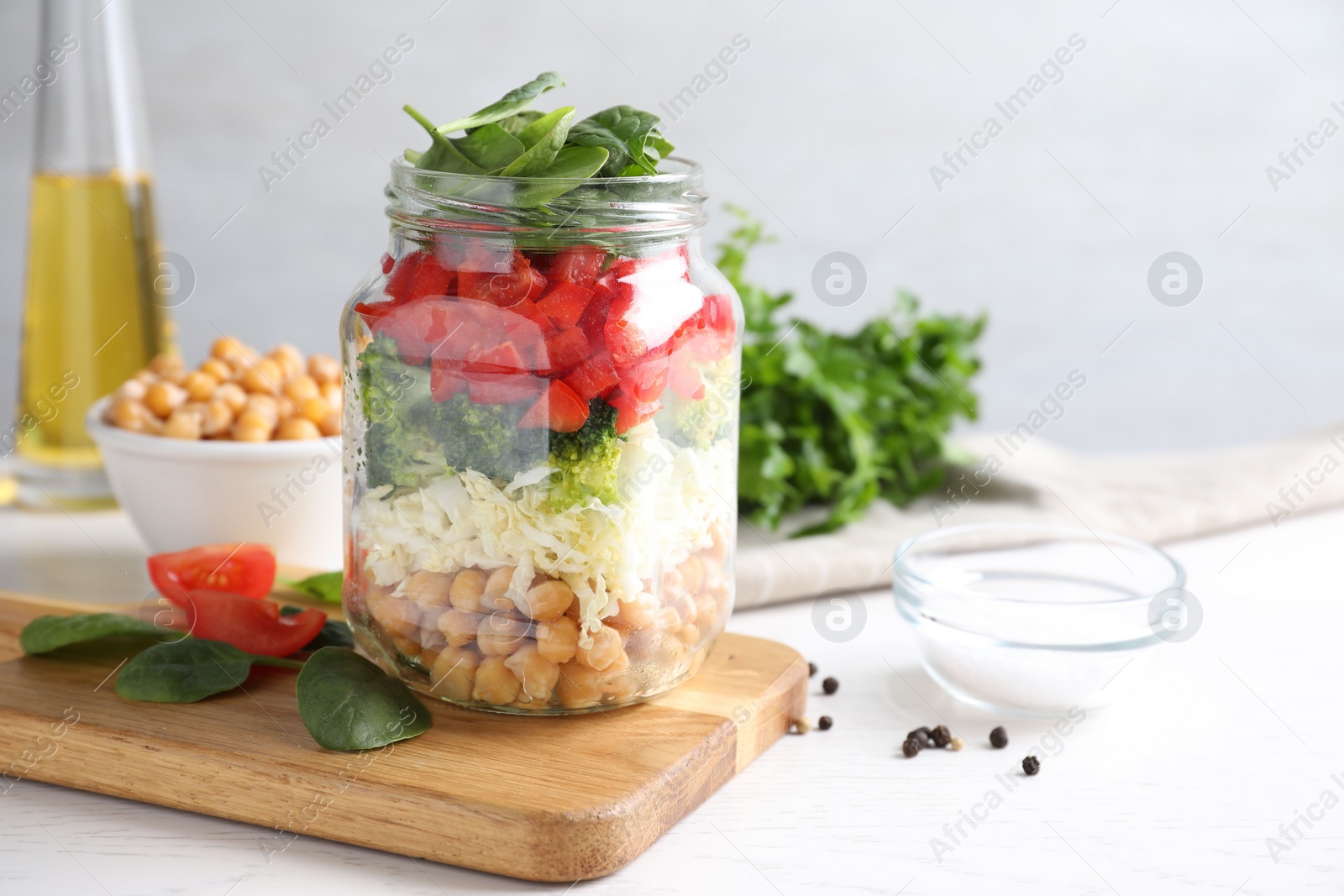 Photo of Healthy salad in glass jar on white table