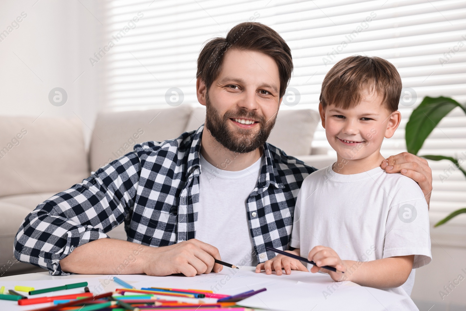 Photo of Family portrait of happy dad and son at table indoors