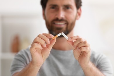 Stop smoking concept. Man breaking cigarette on blurred background, selective focus