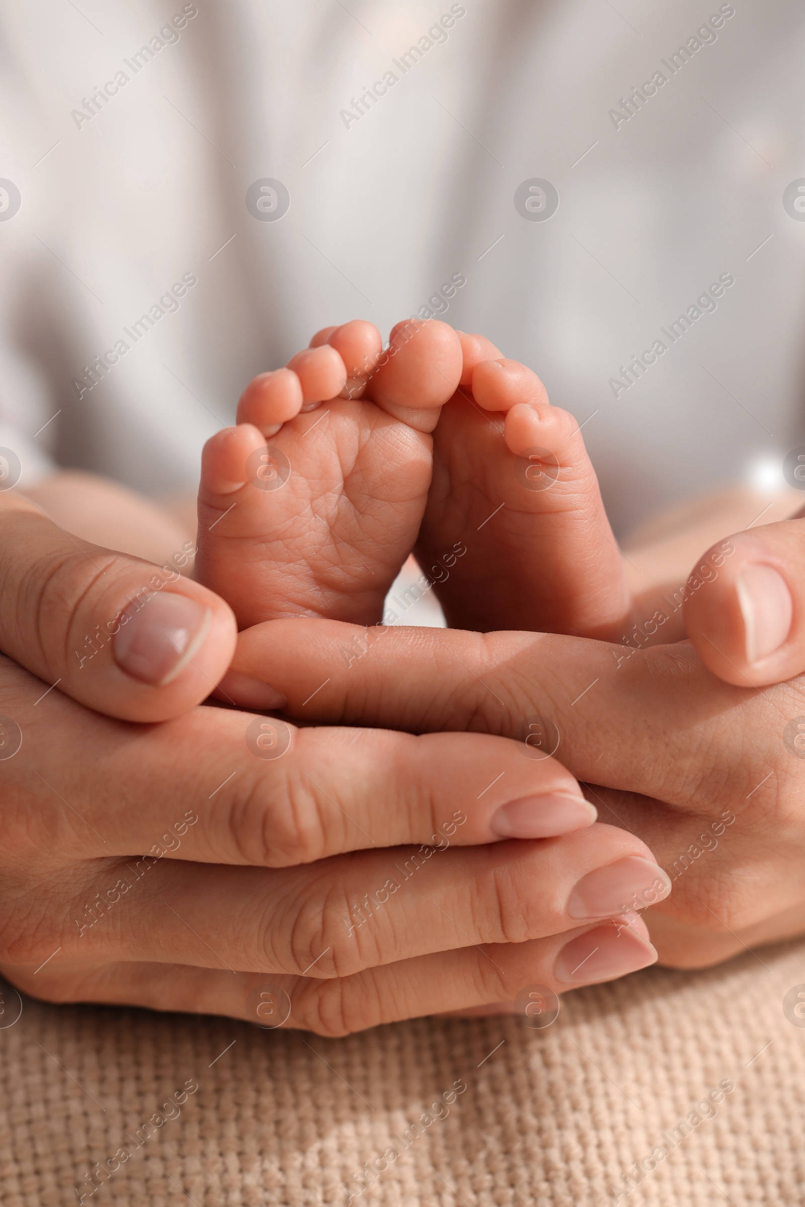 Photo of Mother holding her newborn baby, closeup view on feet. Lovely family