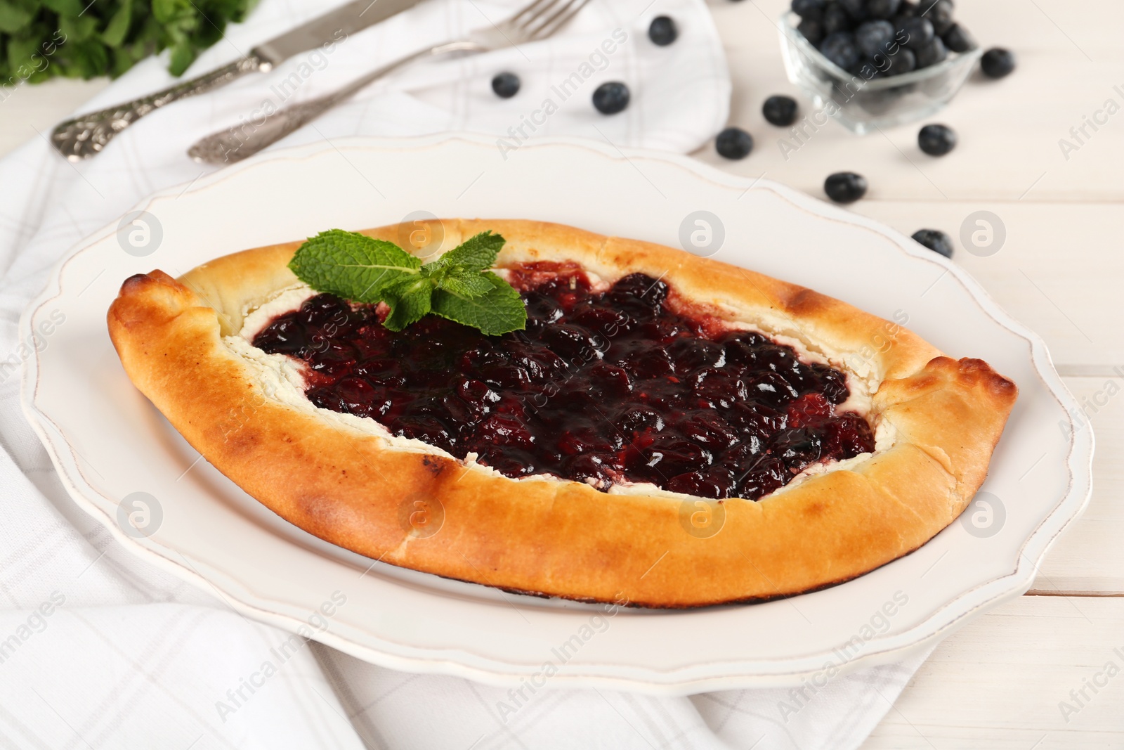 Photo of Delicious sweet cottage cheese pastry with cherry jam served on white wooden table