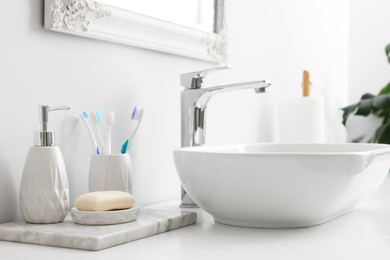 Photo of Different bath accessories and personal care products near sink on bathroom vanity