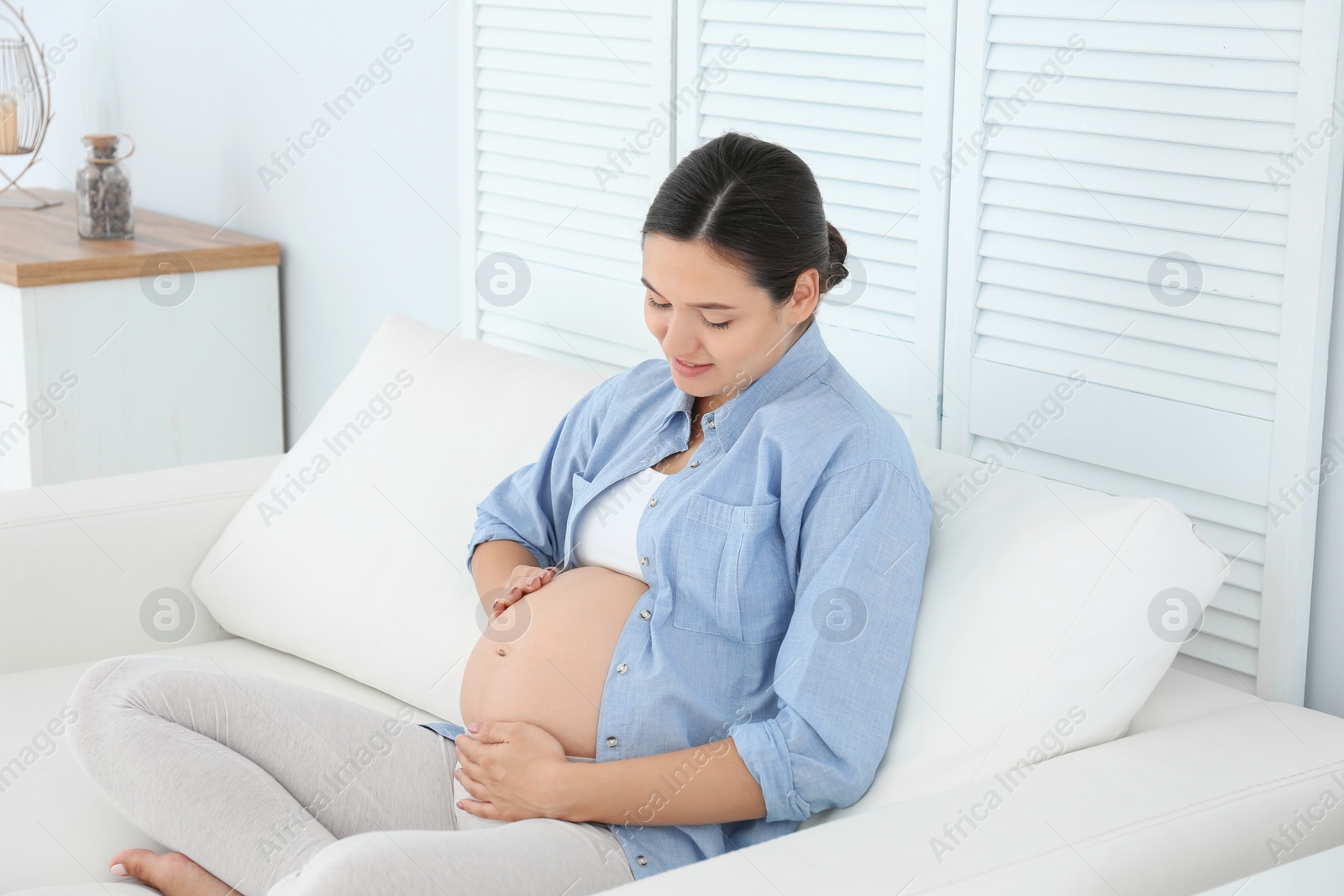 Photo of Beautiful pregnant woman sitting on sofa at home