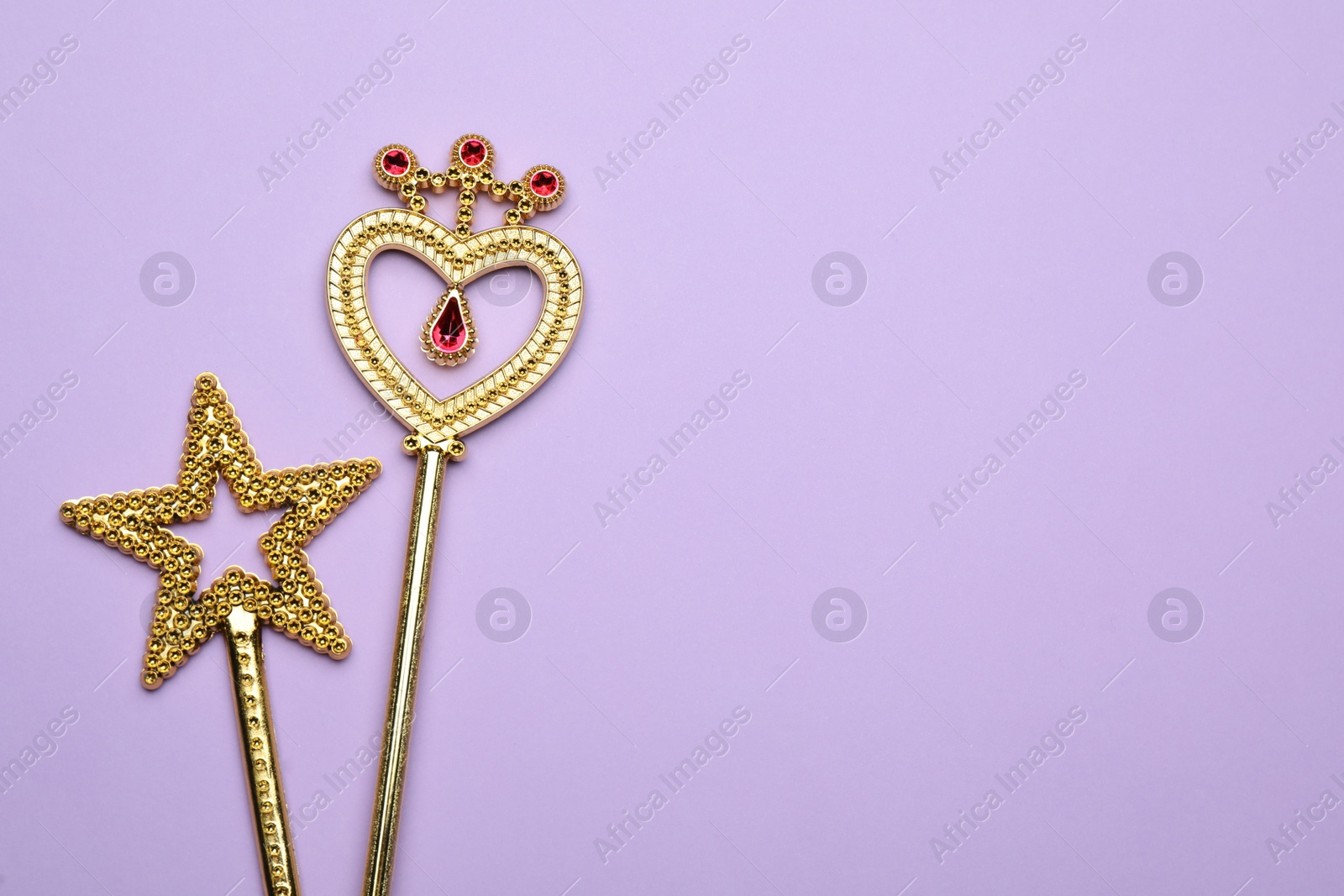 Photo of Beautiful golden magic wands on lilac background, flat lay. Space for text